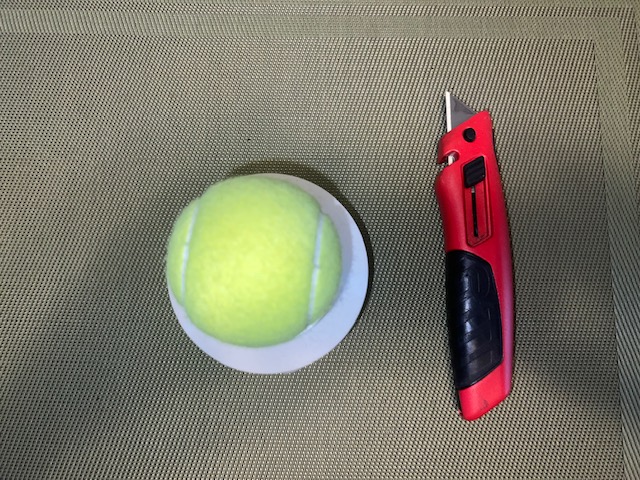 Tennis ball inside PVC pipe fitting ready to cut